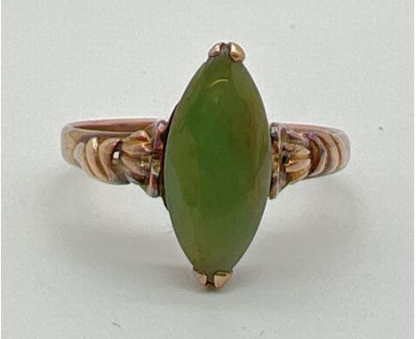 A 9ct gold dress ring set with a marquise cut jade stone. Decorative detail to shoulders. Marked 14K to inside of band. Ring 