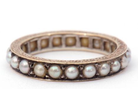 Precious metal and seed pearl eternity ring, the engraved and chased shank with a continuous row of small grey seed pearls, s