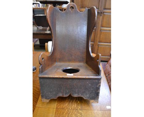 A Mid 19th Century Oak Child's Rocking/Commode Chair, with scrolled handle and winged sides above a boarded seat with apertur