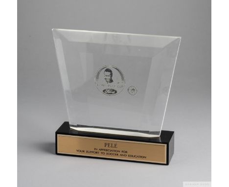 A trophy presented to Pelé composed of a clear acrylic plaque etched with a portrait of Peléover the words "Ford/ Pelé Cup", 