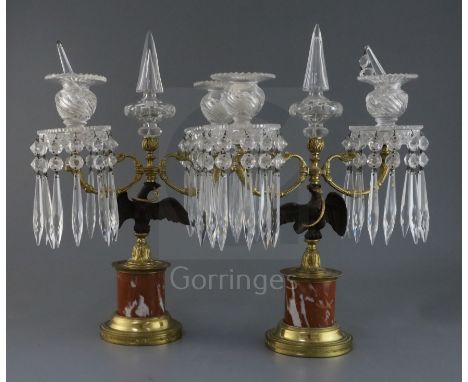 A pair of French Empire style gilt bronze and ormolu candelabra, with cut glass spires and sconces hung with icicle drops, on