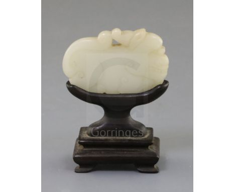 A Chinese white jade 'lion-dog' plaque, 18th century, the stone of good even tone with tiny inclusions, 6cm, wood standProven