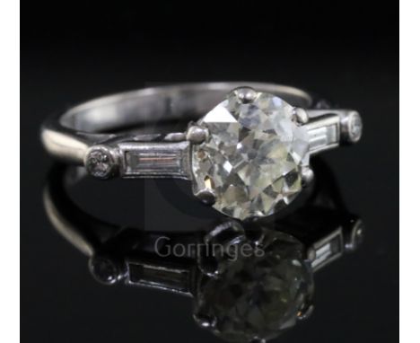 A mid 20th century 18ct white gold and single stone diamond ring with baguette and round cut diamond set shoulders, the centr