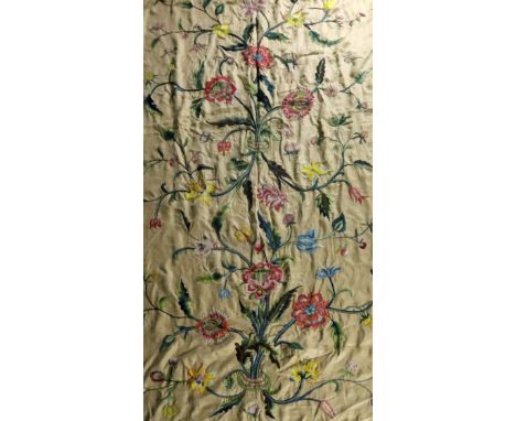 A pair of cream ground crewel worked curtains in the Jacobean style, worked in polychrome wools with flowers and leaves