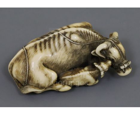 A fine Japanese ivory netsuke of an ox and calf, signed Tomotada, Kyoto School, c.1760-80, with horn inset eyes, engraved sig