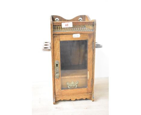 A late 19th / early 20th century smokers cabinet with glass front door, two pipe holders to the side and pierced brass galler