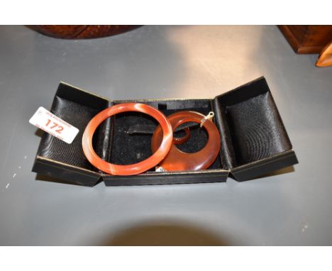 A small orange agate bangle, internal diamater approx 55mm, a matching band ring, size J and a circular pendant with gold pla