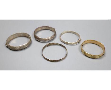 Four assorted silver bangles and a gold plated bangle.