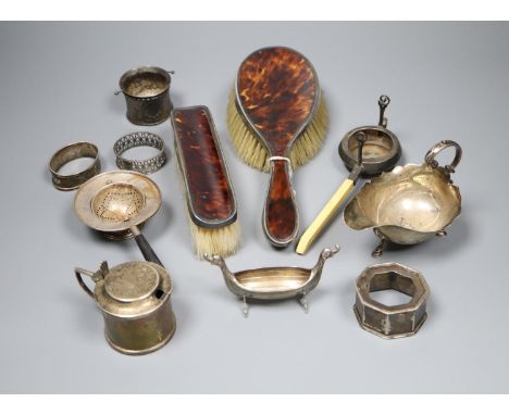 A silver mustard pot, silver sauceboat, three silver and one sterling napkin ring, two silver tea strainers etc.