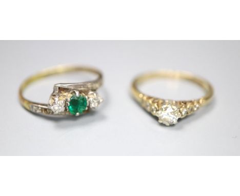 An 18ct and plat, emerald and diamond set three stone crossover ring, with diamond set shoulders, size P, gross 2.2 grams and