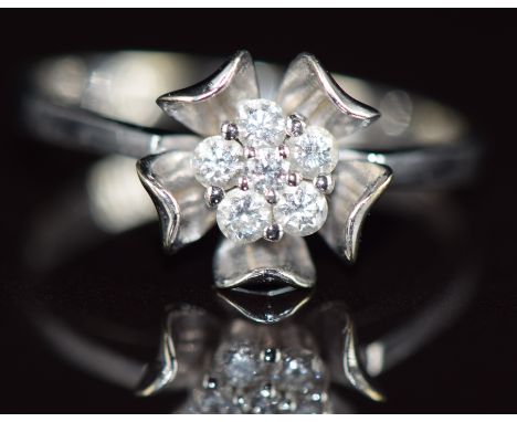 A 9k white gold ring set with round cut diamonds in a flower cluster, 1.8g, size K