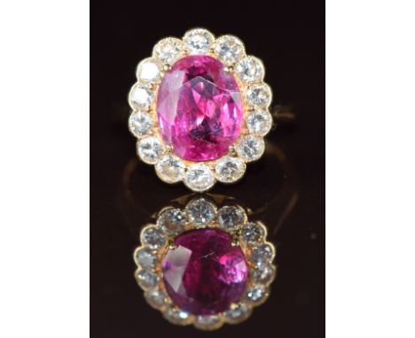 An 18k gold ring set with an oval cut natural unheated pink sapphire of approximately 3.68ct surrounded by sixteen graduated 