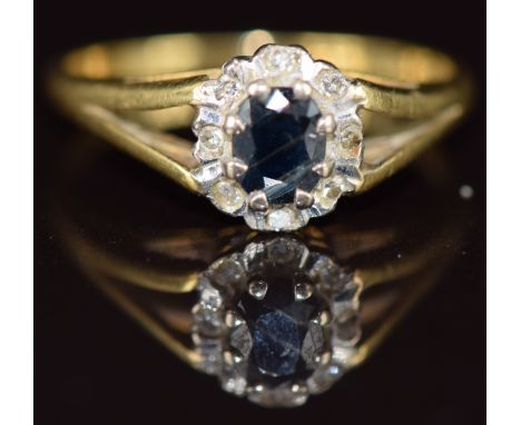 An 18ct gold ring set with an oval cut sapphire surrounded by diamonds, 2.5g, size J