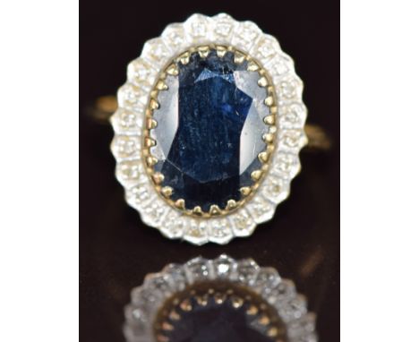 A 9ct gold ring set with an oval cut sapphire surrounded by diamonds, 4.4g, size T