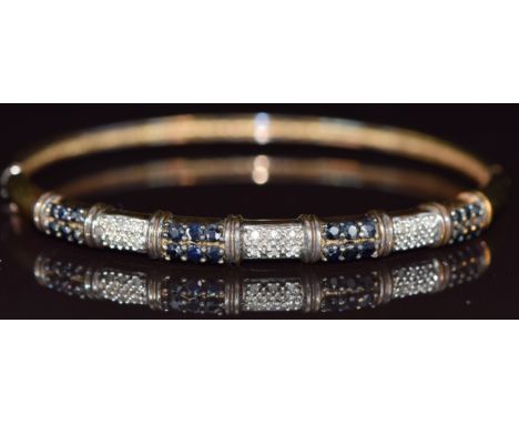 A 9ct gold bangle set with sapphires and diamonds in seven panels, 11g, 6 x 5cm