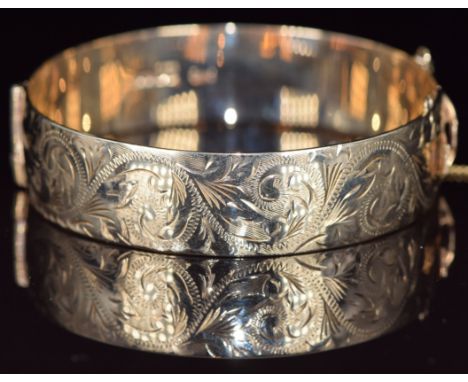 A 9ct gold bangle with engraved scrolling decoration, 44.1g, 5.7 x 6cm