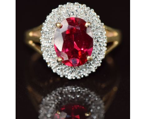 A 9k gold ring set with an oval cut synthetic ruby surrounded by diamonds, 3.6g, size M