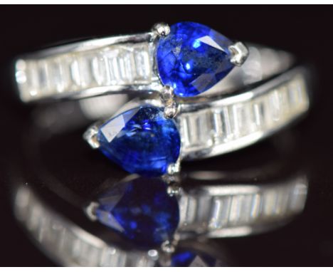 An 18k white gold ring set with two pear cut sapphires, each approximately 0.5ct and baguette cut diamonds to the shoulders, 