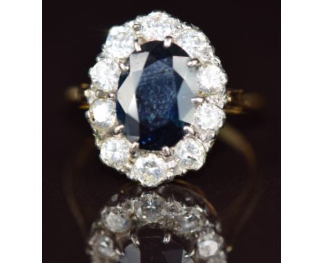 An 18ct gold ring set with an oval cut sapphire of approximately 2.4ct surrounded by ten round cut diamonds, each approximate