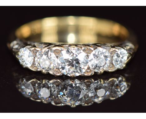 A c1910 18ct gold ring set with five diamonds, the centre diamond approximately 0.4ct, with scrolling setting, 3.3g, size L