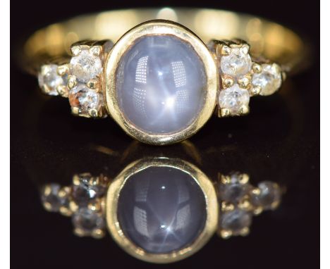 An 18ct gold ring set with a star sapphire cabochon and white sapphires, 4.3g, size O