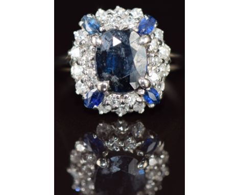 An 18ct gold ring set with an oval cut sapphire of approximately 1.6ct surrounded by sapphires and diamonds, 5g, size O