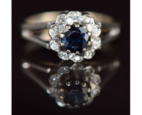An 18ct gold ring set with a round cut sapphire surrounded by diamonds, 4.6g, size L