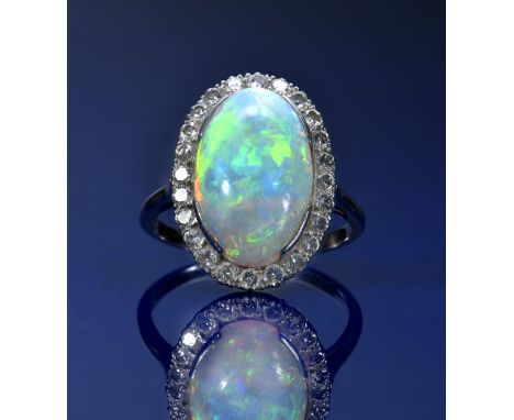 A platinum ring set with an opal cabochon of approximately 4.3ct&nbsp;surrounded by 24 round cut diamonds, 5.4g, size O