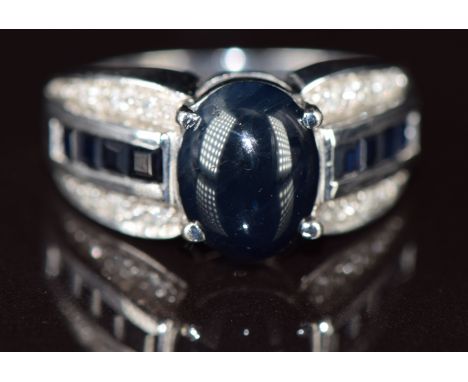 A 9k white gold ring set with a sapphire cabochon, calibre cut sapphires and diamonds, 5g, size N