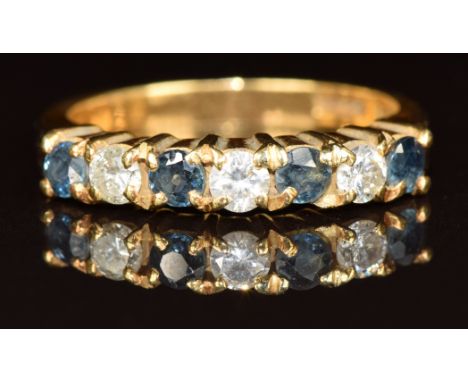 An 18ct gold half eternity ring set with three diamonds and four sapphires, 4.9g, size M