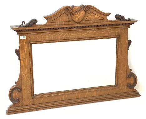 Edwardian oak overmantle mirror, the swan neck pediment centred by shield, over rectangular plate, the frame decorated with c