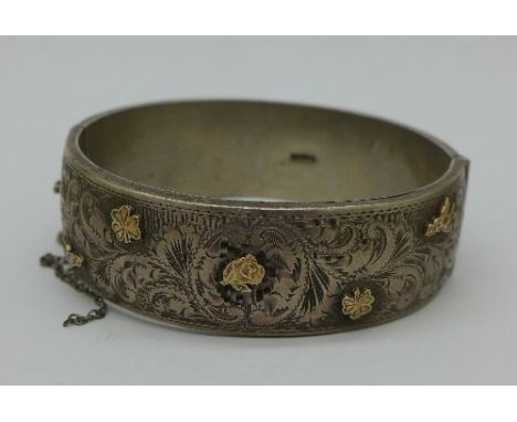 A silver bangle with applied gold decoration, safety chain a/f