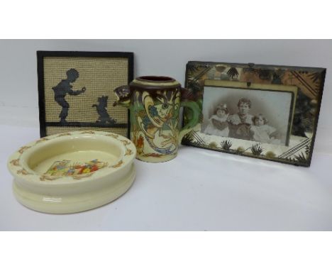 A Doulton Bunnykins bowl, a framed embroidery, a glass photograph frame and a studio pottery fish jug marked C.H. Branham