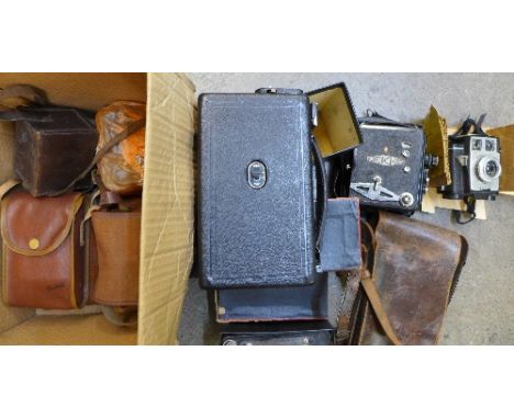 A collection of early cameras including two folding cameras, four box cameras including a Bakelite Baby Brownie, two cine cam