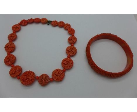 A carved coral necklace and a coral coloured bangle, necklace fastener a/f