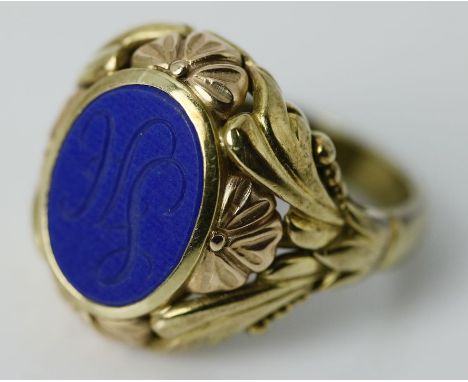 Ring. 585/000 GG, brutto 6,9 g. Floral reliefierter Ringkopf mit ovalem Lapislazuli-Tafelstein, dieser mit graviertem Monog. 