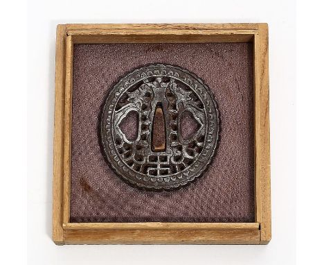 Tsuba. Eisen, teils dunkel patiniert und durchbrochen gearbeitet. Japan, wohl Edo-Periode. D. 7x 6,5 cm. In Holzschatulle.