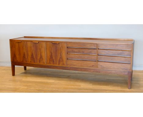 A Danish rosewood sideboard, c.1960s, of long low form with plain top over two banks of three graduated cutlery and napery dr
