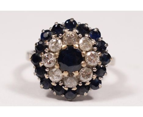 An 18ct white gold sapphire and diamond cluster ring, claw set with brilliant cut stones, diamond weight estimated 1ct, colou