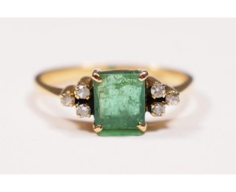 A 14K gold emerald and diamond ring, claw set with an emerald cut stone, 6 x 5mm flanked by single cut diamond trefoils, L, 2