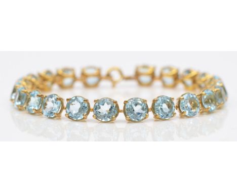 A gold and blue topaz line bracelet, claw set with brilliant cut stones, tested as 9ct gold, silver gilt clasp, 17cm, 14gm