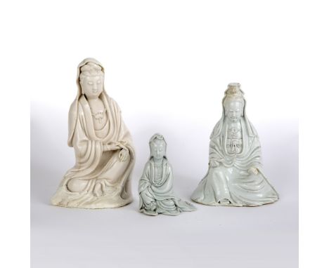 Three dehua figures of Guanyin Chinese, 19th Century two modelled holding a scroll to one hand, with flowing robes by her sid