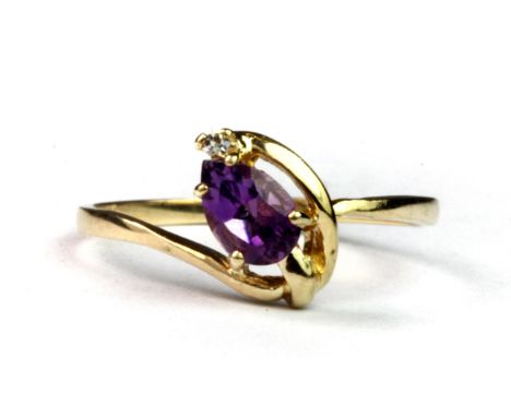 A 10ct yellow gold (stamped 10K) ring set with a pear cut amethyst and a diamond (L.5).