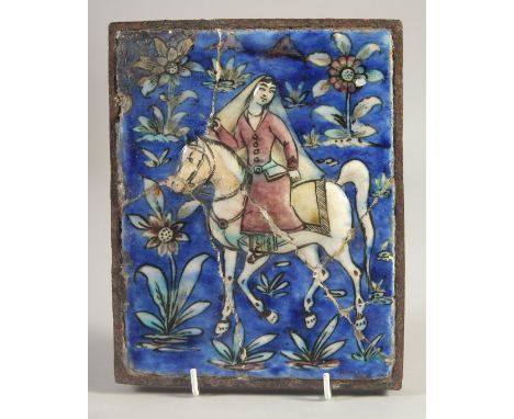A PERSIAN QAJAR GLAZED POTTERY TILE, depicting a figure on horseback and flora, inset within an antique metal frame, tile 20c