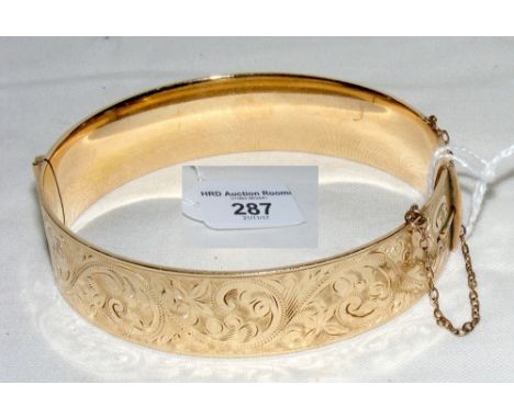 A gilt bangle with engraved decoration - 7cm diameter