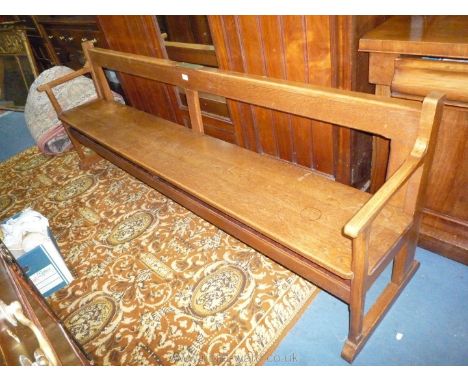 A heavy Oak Hall seat/pew having open arms and standing on sleigh type feet, a plaque attached reads ''In Loving memory of Ma