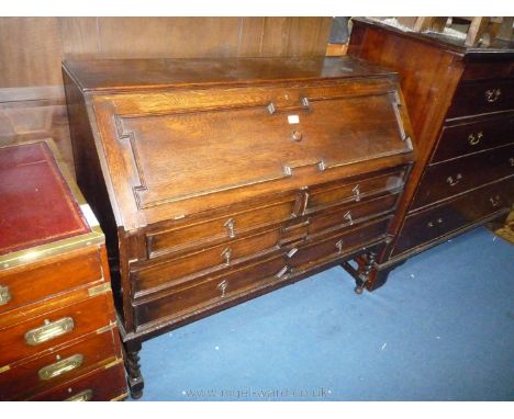 An early 20th c. Oak Bureau, the slope opening to reveal an interior with pigeon holes and two small trinket drawers and unus