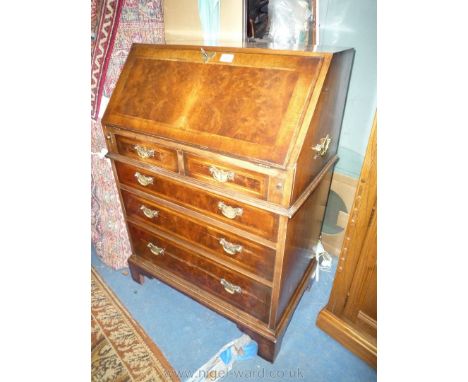 A Walnut and Mahogany cross-banded Bureau of diminutive proportions, the slope opening to reveal an interior with pigeon hole