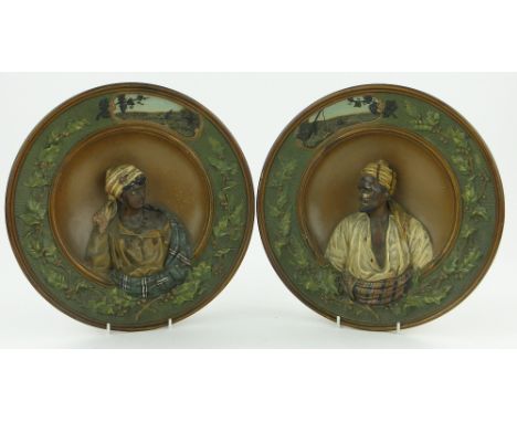 A pair of German relief plaques,
with portrait studies within holly decorated borders, impressed Musterschutz, 12".