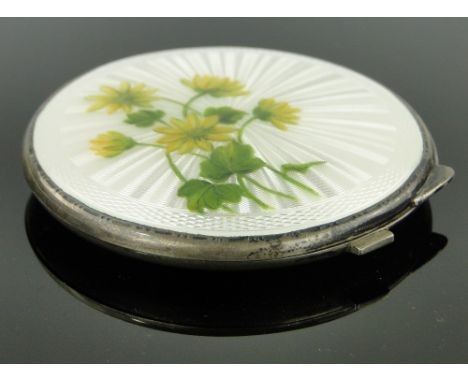 A silver and white enamel compact,
with painted floral spray Birmingham 1949, 7cm across.